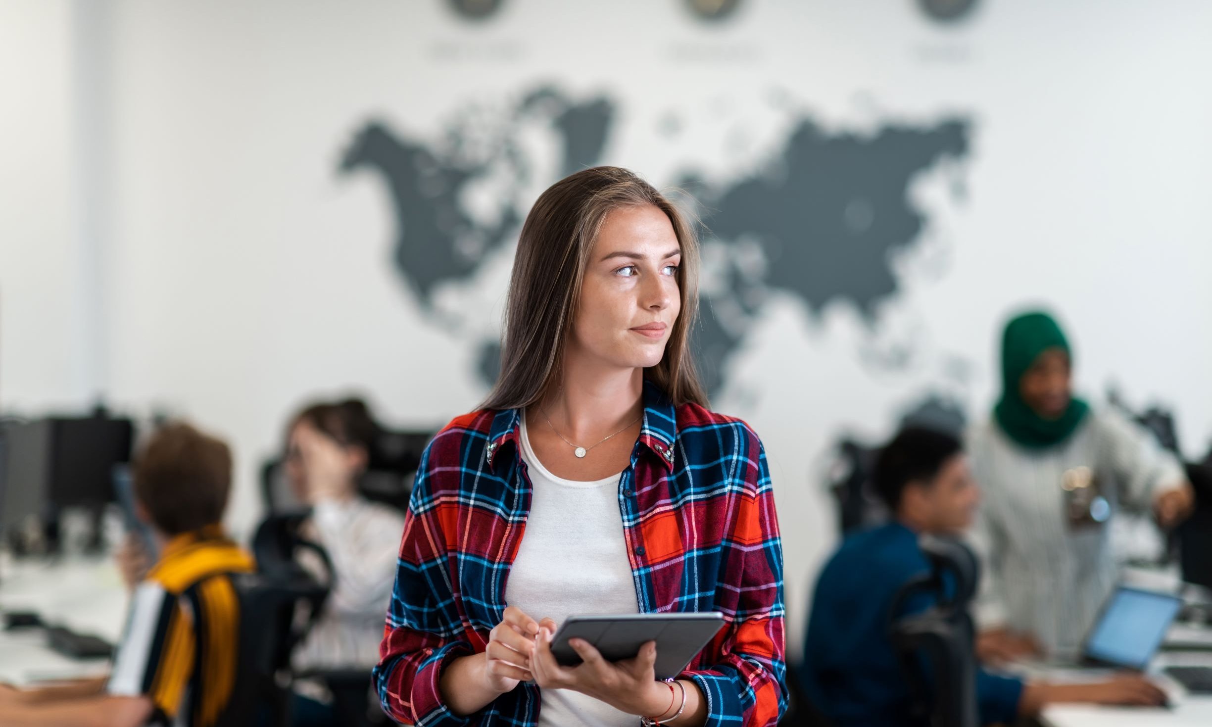 young woman with tablet standing in front of a world map