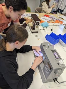 DIY Wearables: Blick auf Tisch mit Schülerinnen, Nähmaschinen und Materialien