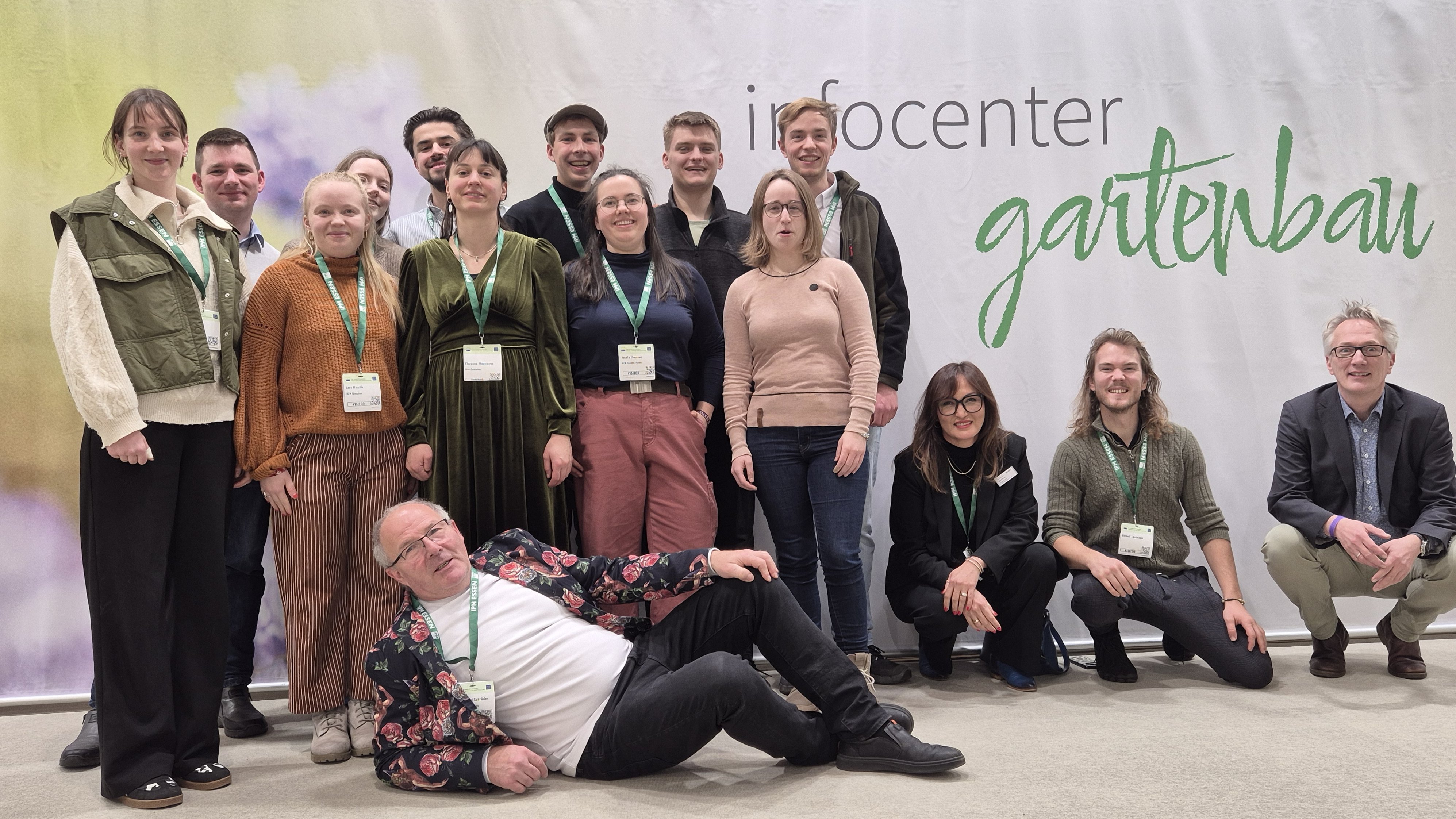 Eine Personengruppe steht oder sitzt vor einer Wand mit Aufschrift "Infocenter Gartenbau"