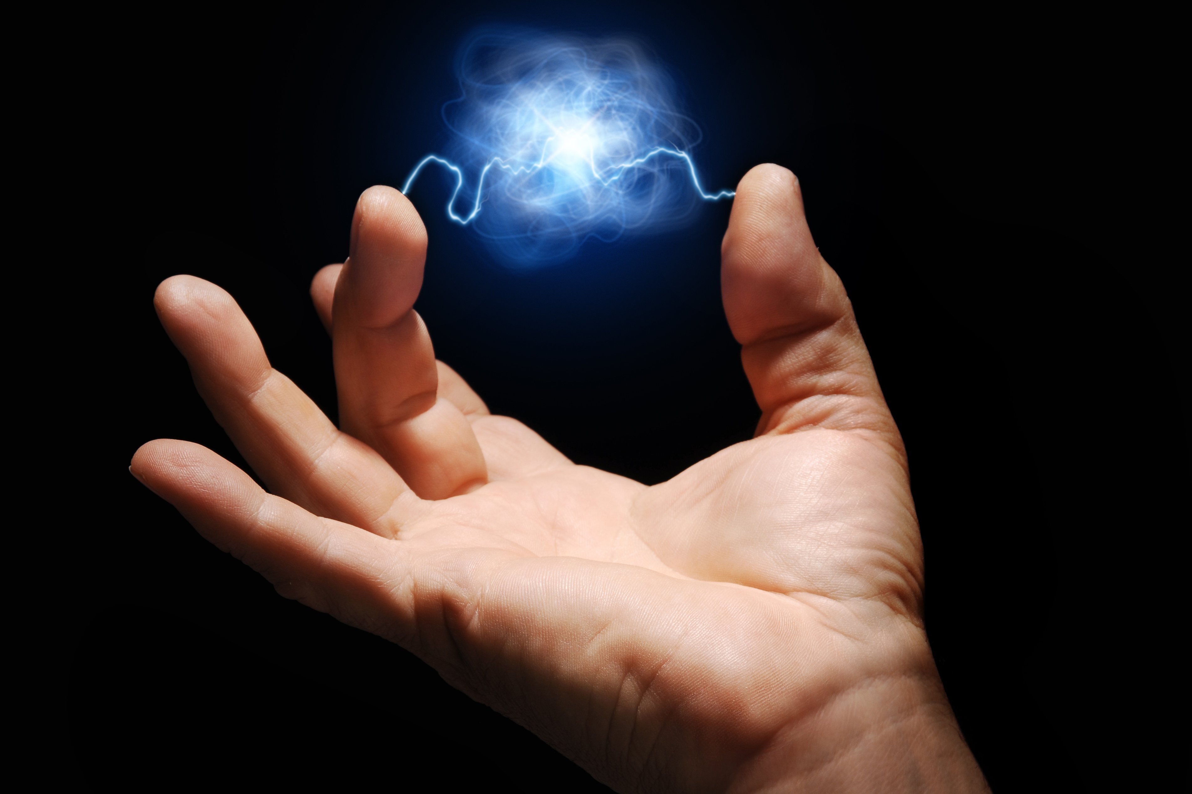 Hand hält Energieblitz zwischen den Fingern.