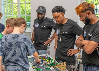 Drei Männer stehen hinter einem Tisch mit einem Lego-Aufbau