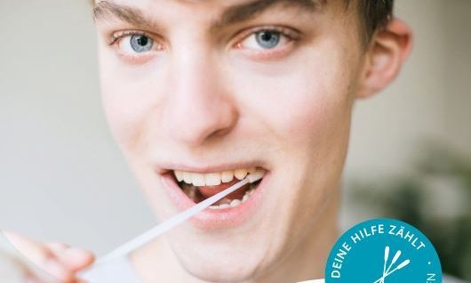 junger Mann macht Schleimhautabstrich mit Wattestäbchen im Mund