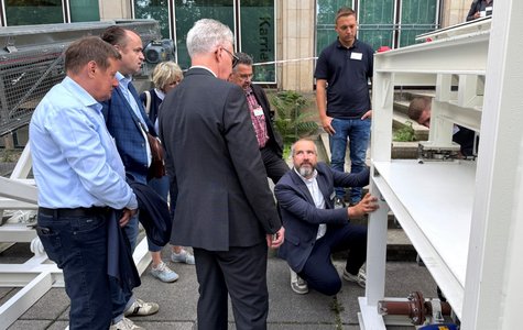 Menschen stehen vor einer technischen Anlage draußen