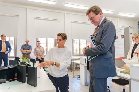 Eine Professorin erklärt dem Minister etwas über ihre Forschung.