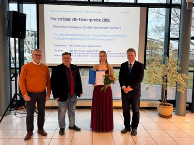 Frau Naumann und ihre Betreuer vor einer Plaketwand mit dem Thema ihrer Abschlussarbeit