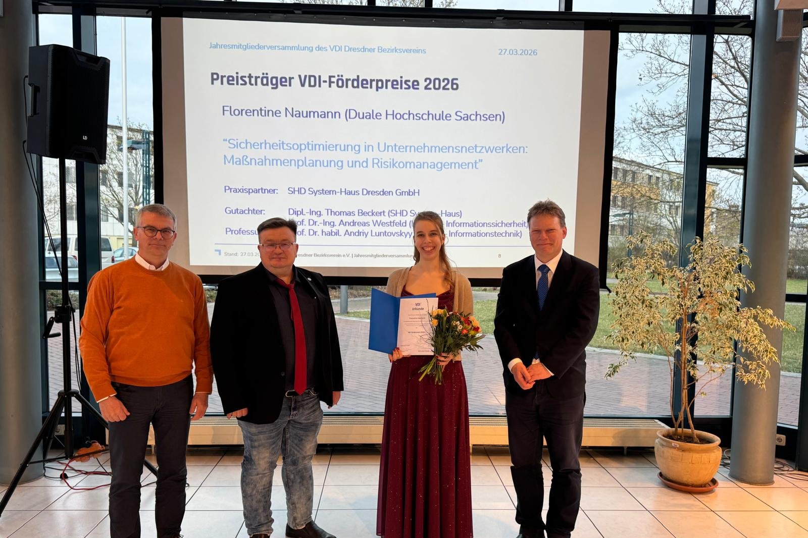 Frau Naumann und ihre Betreuer vor einer Plaketwand mit dem Thema ihrer Abschlussarbeit