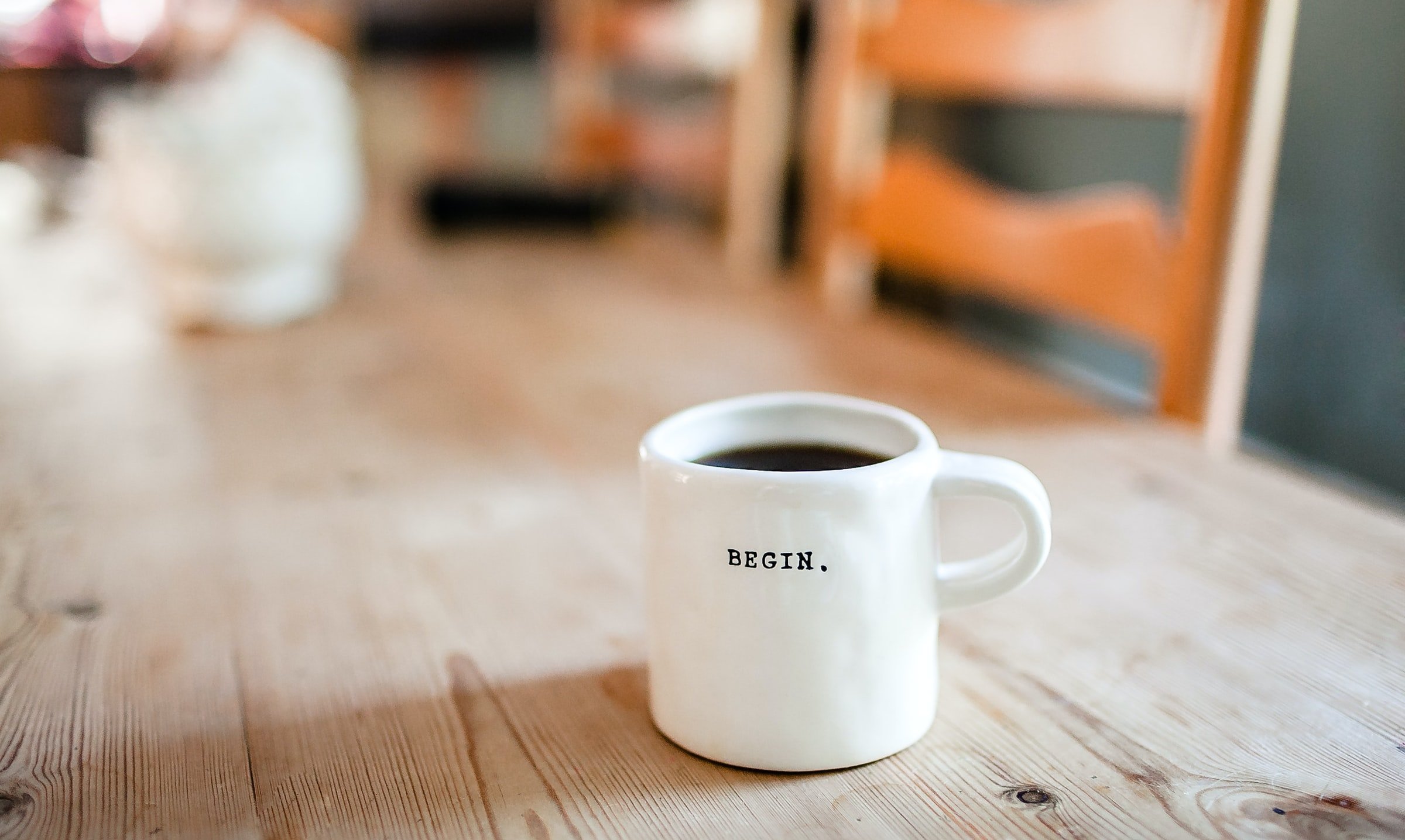 Symbolbild mit Tasse mit Aufschrift "Begin." auf Tisch