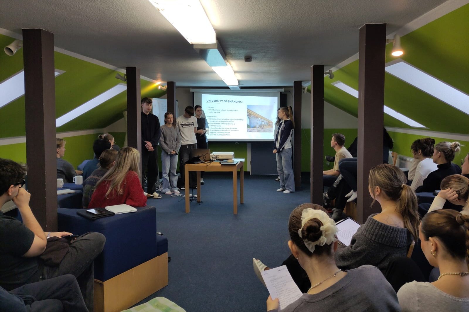 Eine Gruppe von Studierenden sitzt zusammen. Eine Gruppe Studierende hält einen Vortrag.