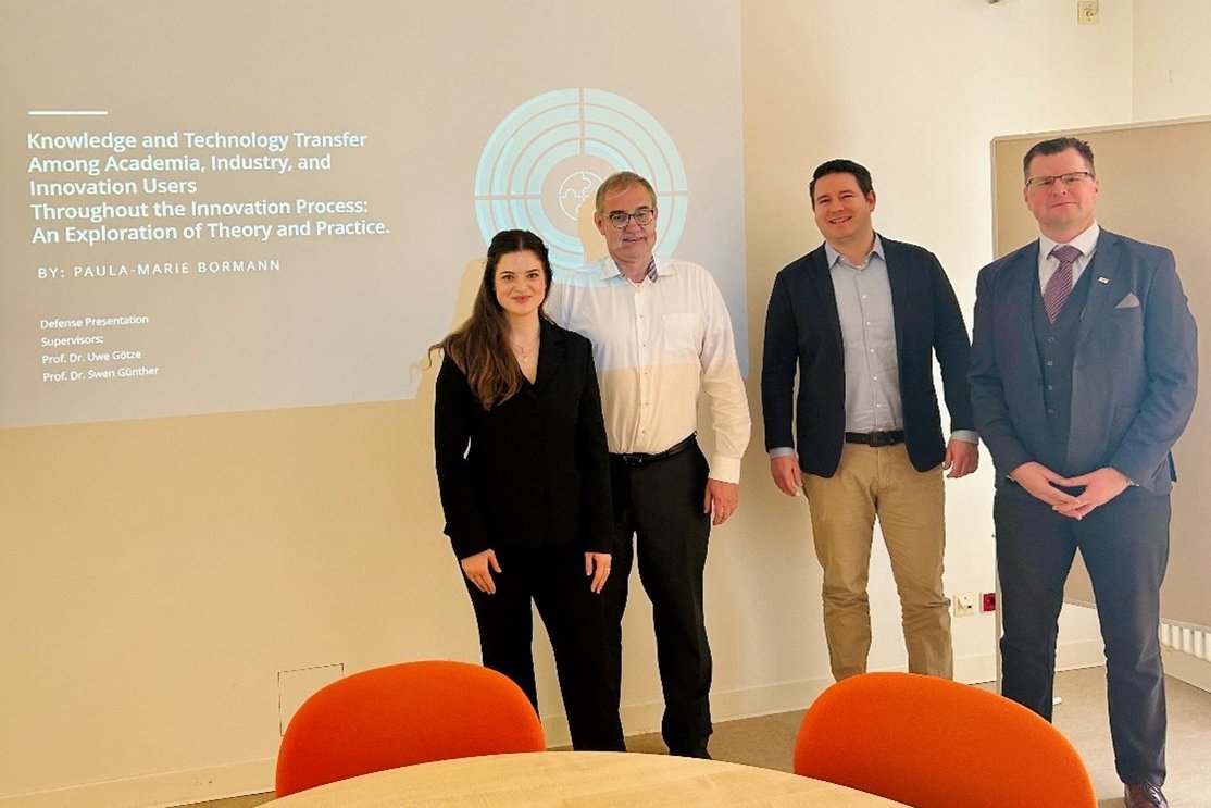 Vier Personen stehen vor ener Wand. Auf die Wand wird eine Folie projiziert.