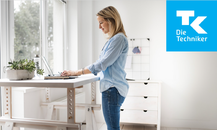 Person steht am Schreibtisch und schaut auf ihren Bildschirm