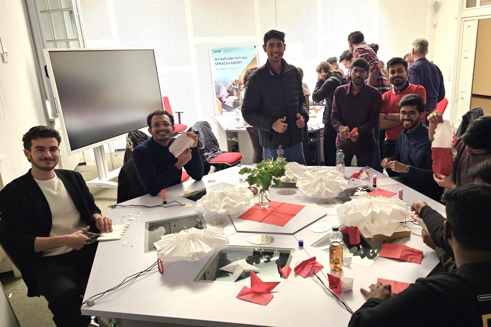 Studierende sitzen gemeinsam um einen Tisch mit gebastelten Sternen.