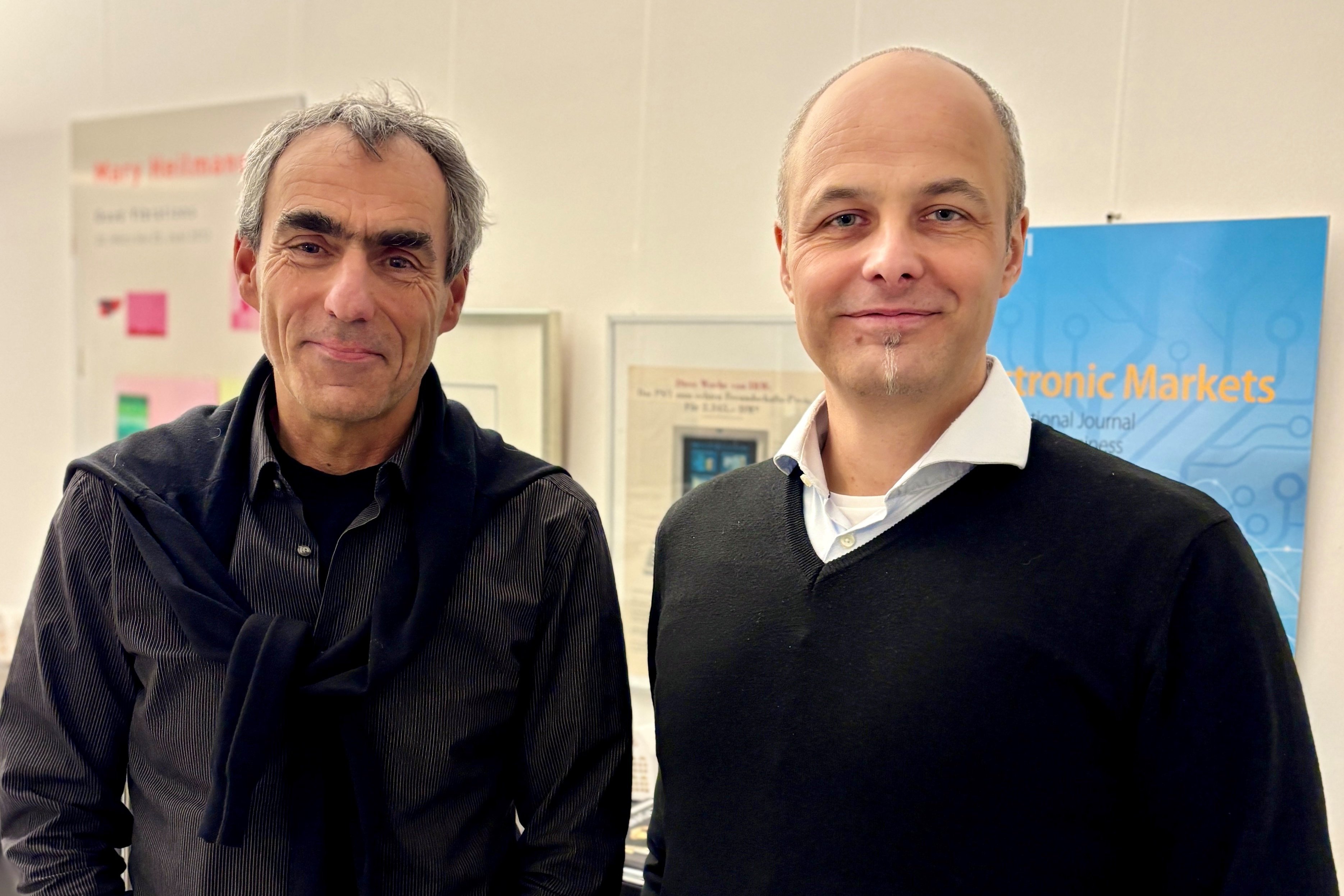 Zwei Männer stehen vor einer Plakatwand